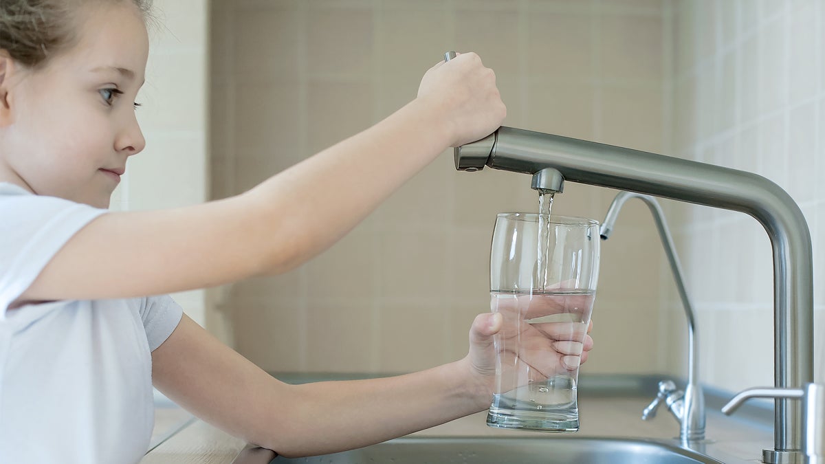 Kind füllt Trinkglas mit Leitungswasser