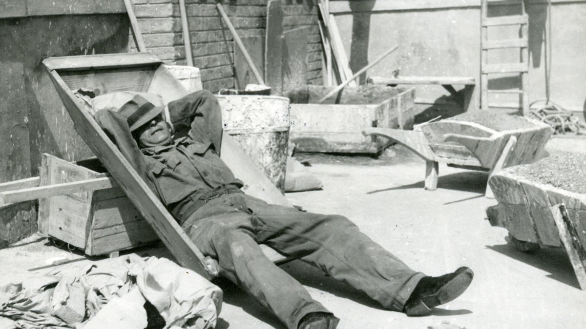 Schwarz-weiß Foto eines Arbeiters der auf der Baustelle eine Pause macht.