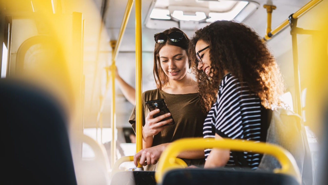 zwei junge Frauen im Bus mit Handy