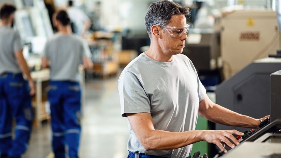 Arbeiter an Maschine Fabriksarbeiter bedient Maschine