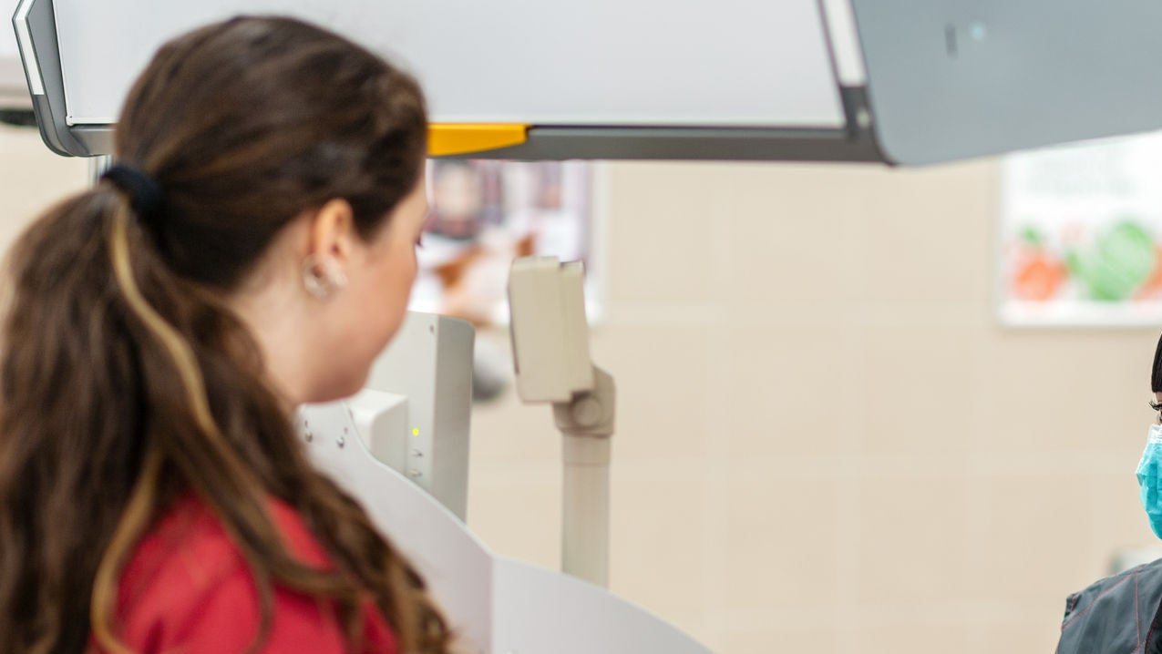 A young woman in a medical mask and gloves, working at the checkout in a supermarket. In the foreground is a customer in a blur. Concept of coronovirus, protection from infection and industrial crisis.