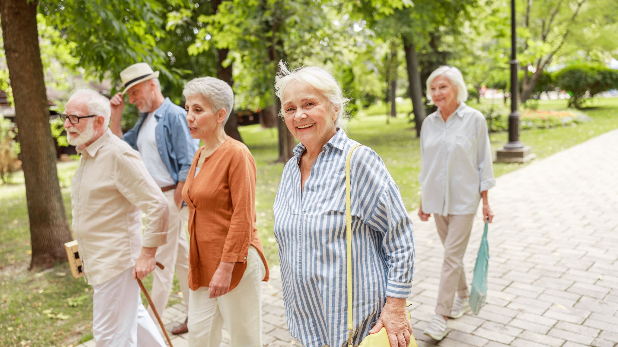 Glückliche Pensionist:innen gehen im Park spazieren