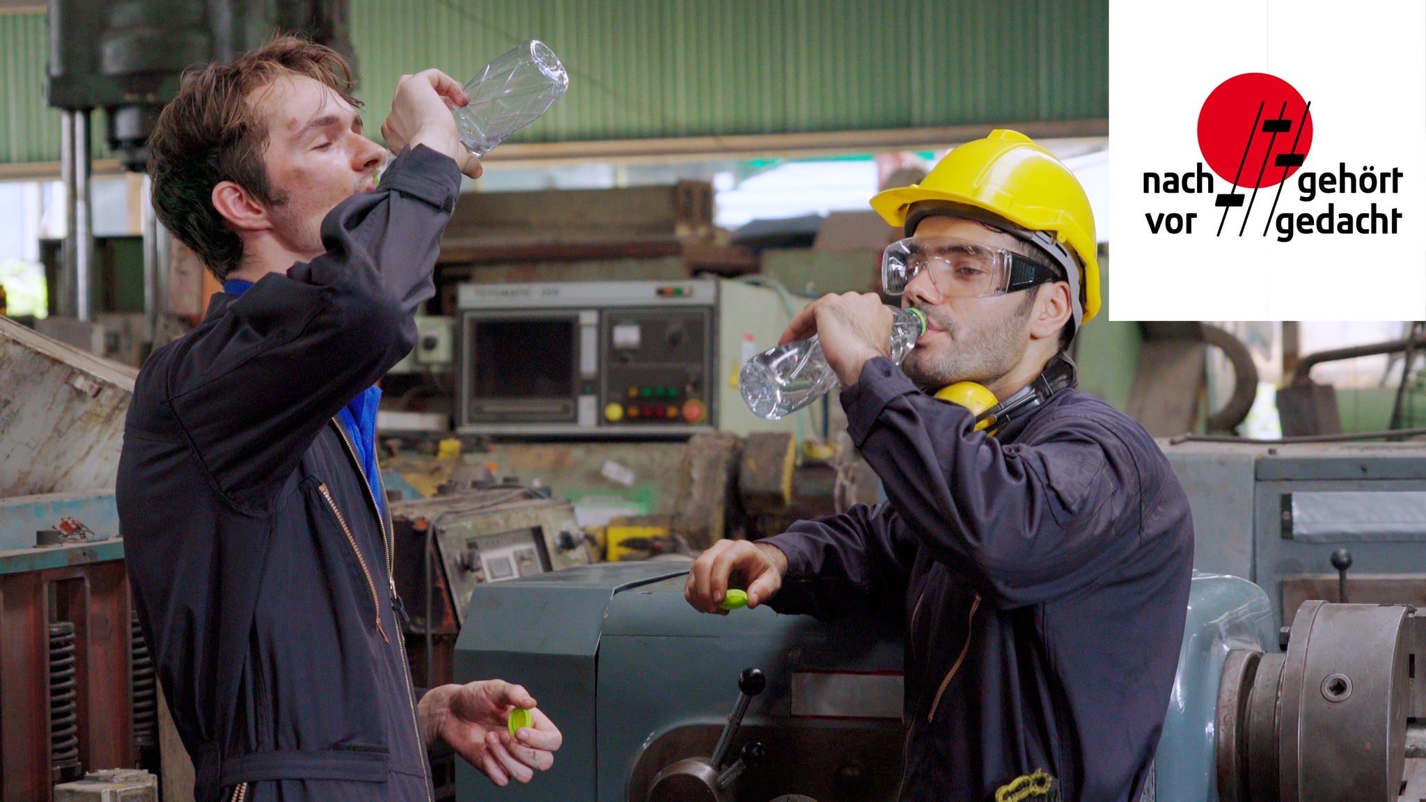 Zwei Arbeiter in Arbeitsschutzkleidung stehen in einer Fabrikhalle und trinken Wasser. In der rechten oberen Ecke ist das "nachgehört - vorgedacht" Podcast Logo platziert
