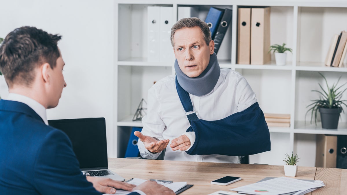 Mann mit gebrochenem Arm in einer Schlinge wird beraten