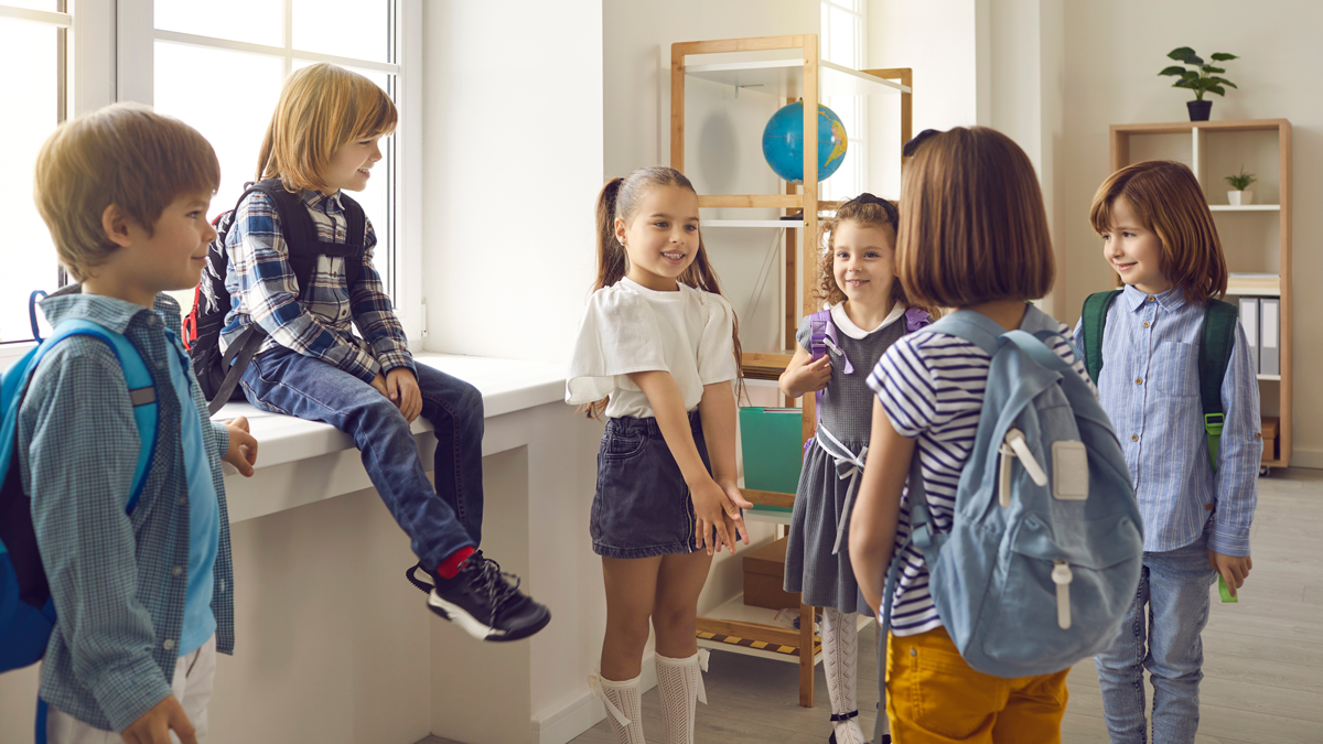 Volksschulkinder stehen in einer Gruppe zusammen und unterhalten sich