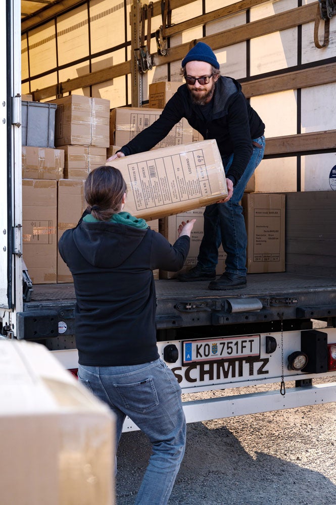 zwei Männer laden die Güter des Hilfstransports aus dem LKW