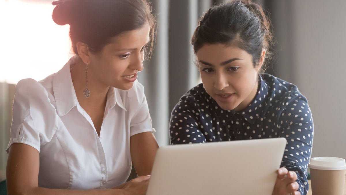 Zwei Frauen im Gespräch, sie schauen gemeinsam in einen Laptop.