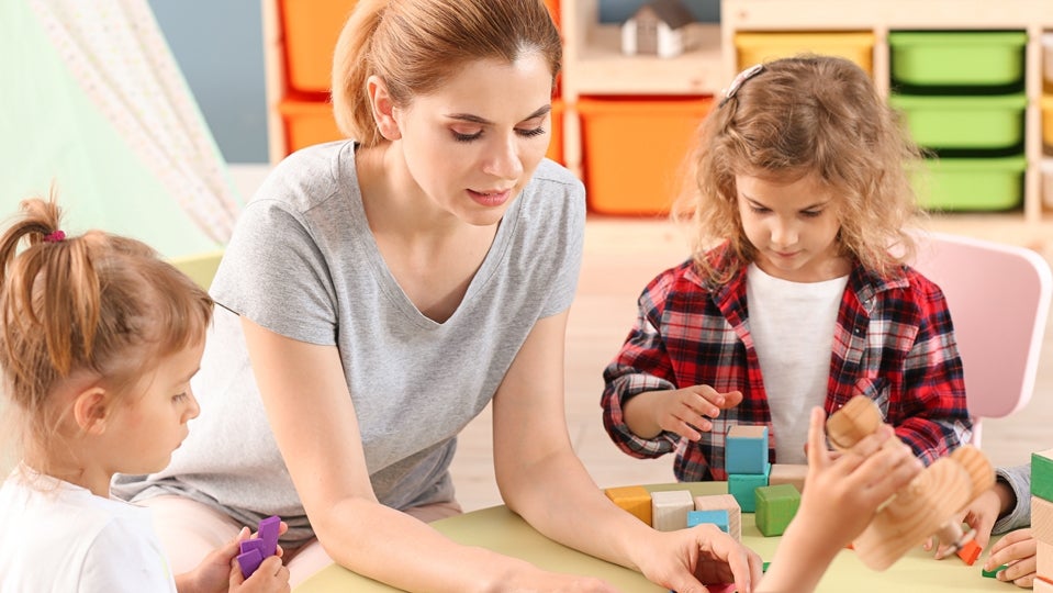 Nursery teacher with cute little children in kindergarten