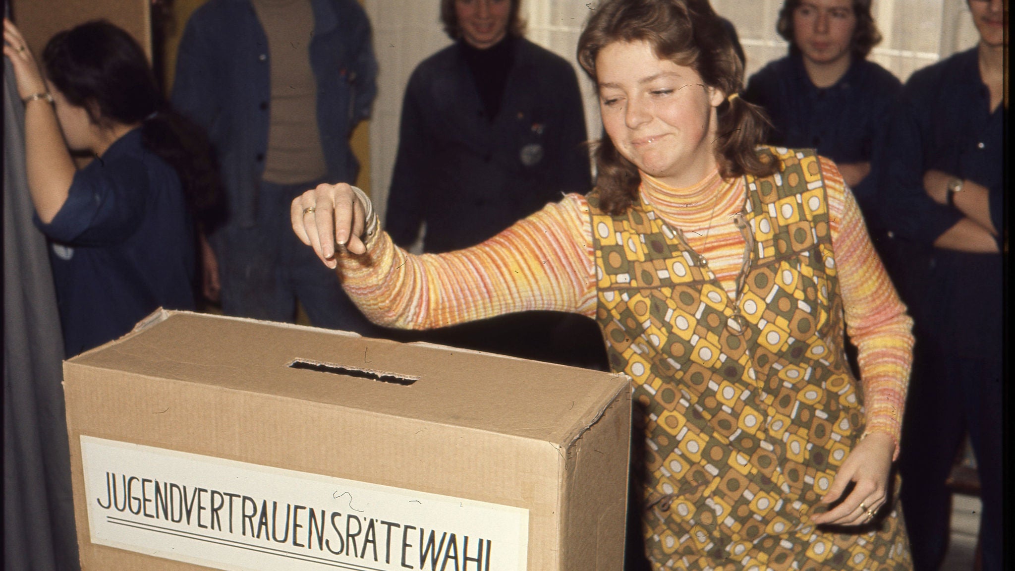 Jugendliche Arbeiterin wirft ihre Stimmkarte in die Wahlurne (o.J.)