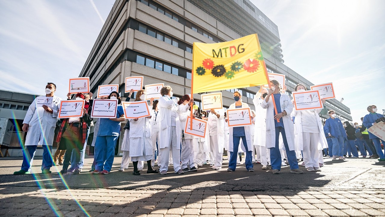 Gesundheitspersonal stehen mit Schildern und Plakaten vor Krankenhaus
